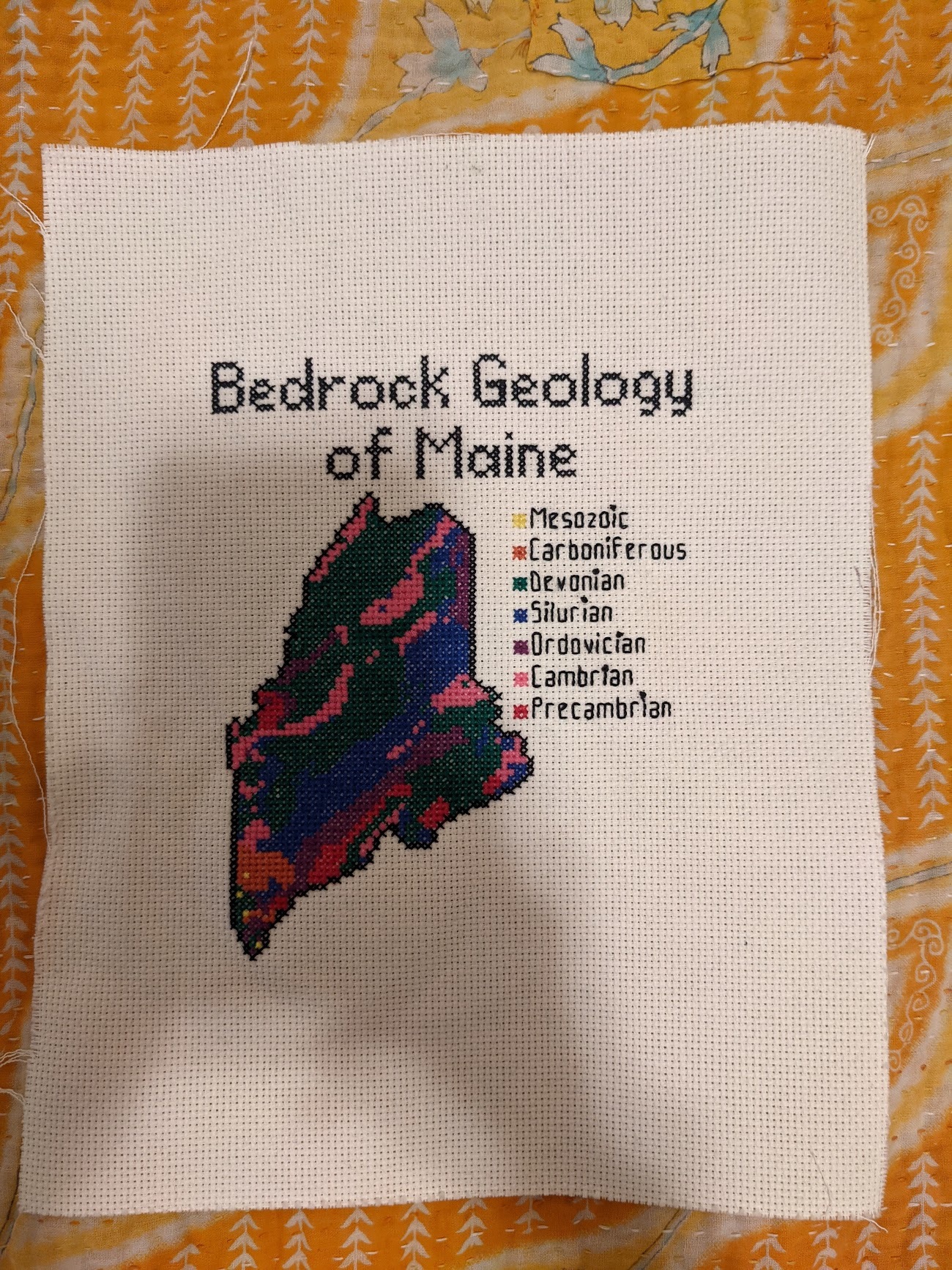 Photo of a cross stitch of the bedrock geology of Maine